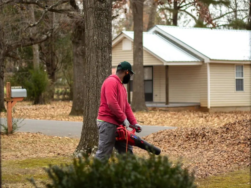 Crew member clearing leaves from a front yard with a leaf blower